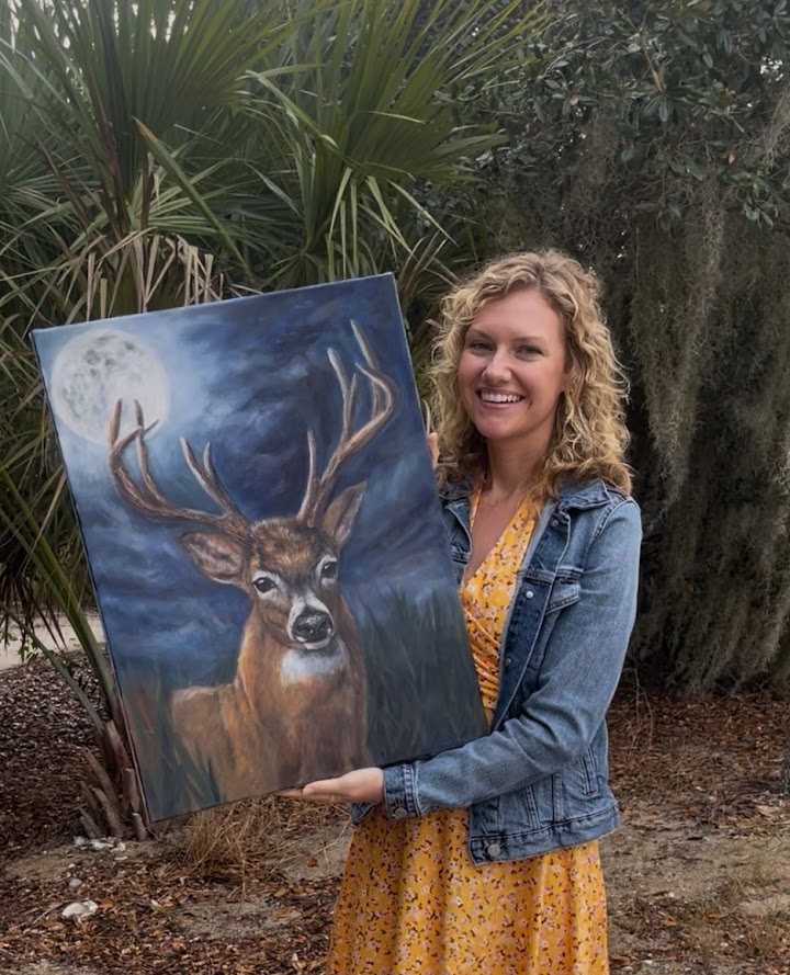 Madison holding a finished deer painting outdoors