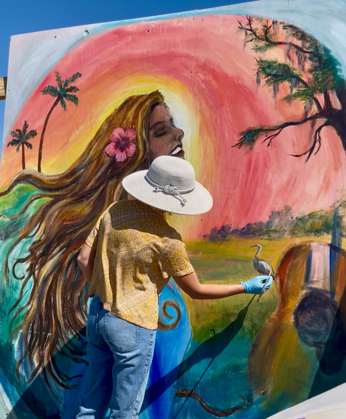 Madison standing before her colorful mural painting
